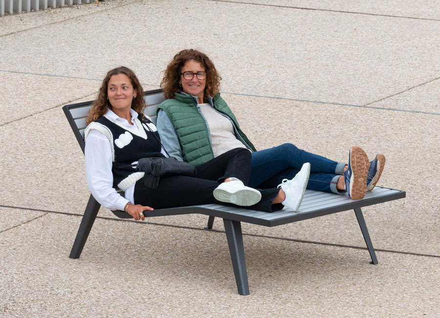 Duo de femmes installées sur Grande chaise longue Michigan aluminium conçu et fabriqué par Aréa mobilier urbain